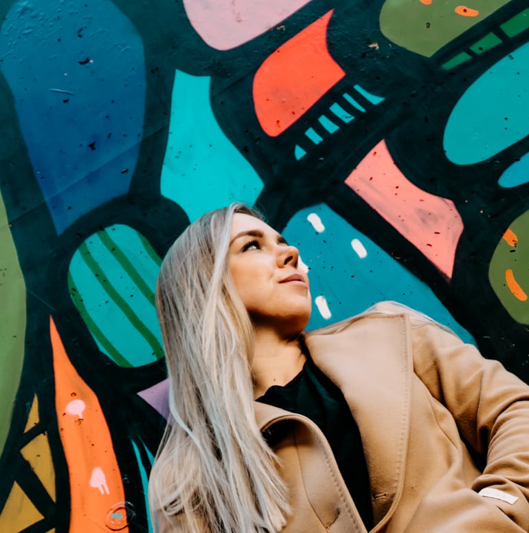 Laura steht vor einer Wand mit Graffiti 